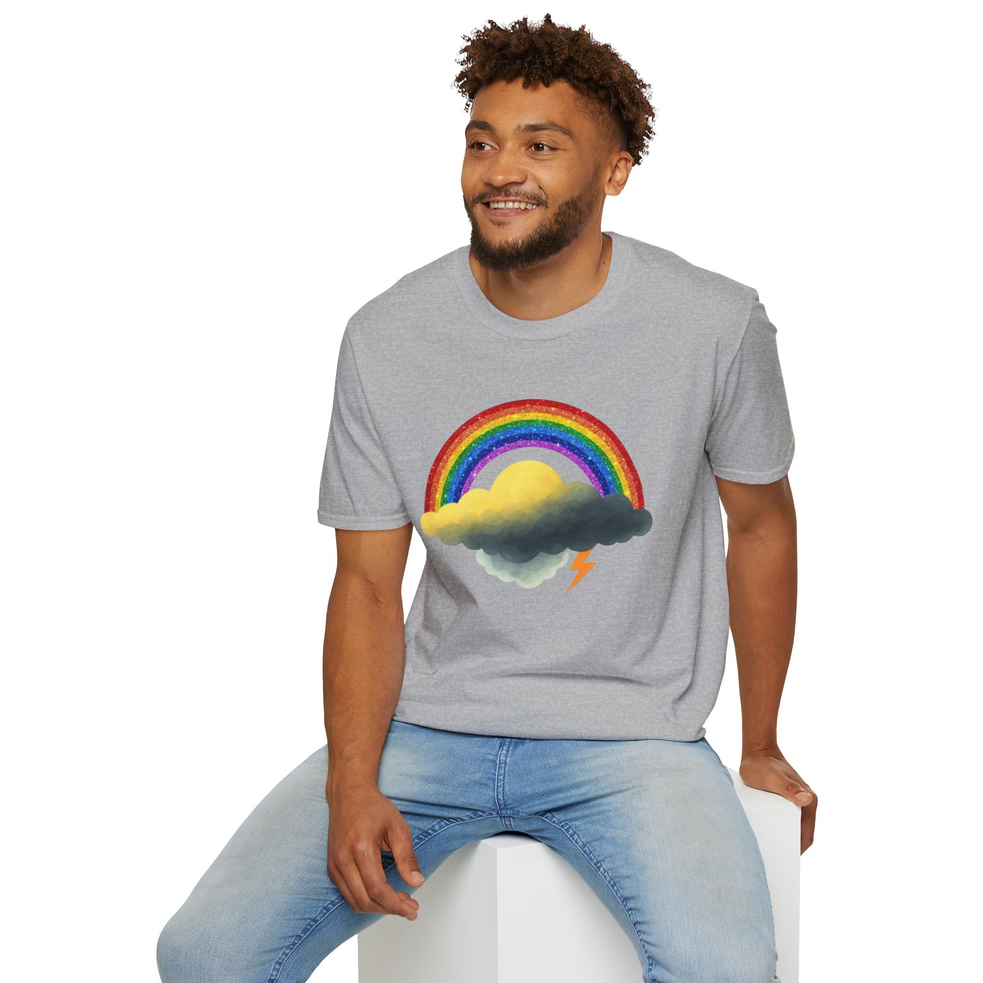 Man wearing a gray t-shirt with a rainbow and Jay cloud design, sitting on a white stool against a white background.