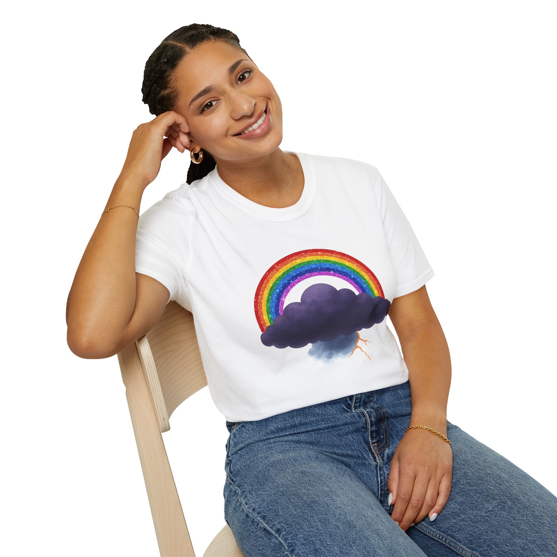 Person wearing a white t-shirt with a rainbow and Tempest cloud design, sitting on a chair against a white background