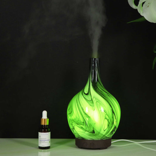 Green marbled diffuser emitting steam with a dropper bottle on a black background